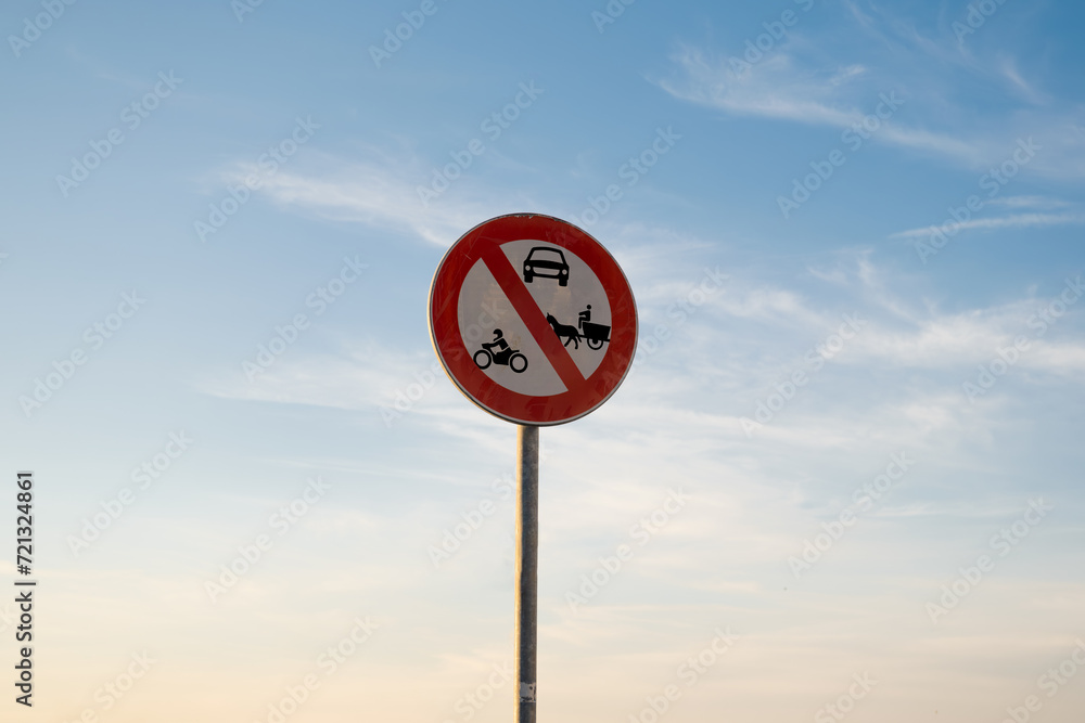 No entry for motorbike Cars or animal-drawn vehicles traffic sign, isolated sunset sky.