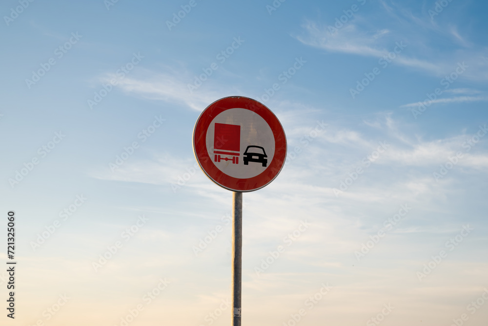 No overtaking by goods vehicles traffic sign, isolated sunset sky.