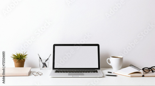 Close up of modern workspace with blank screen laptop, coffee cup, stationery and copy space on white wall background