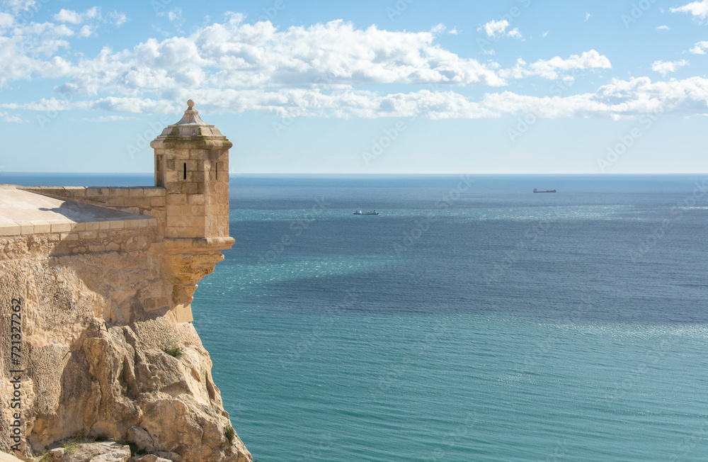 View of the turquoise waters of Mediterranean Sea with a medieval watch tower of Santa Barbara Castle in Alicante, Spain