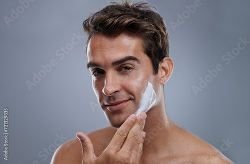 Portrait, shave cream and man with skincare, cosmetics and beauty on a grey studio background. Face, person and model with grooming routine and treatment with beard and moisture with wellness photo