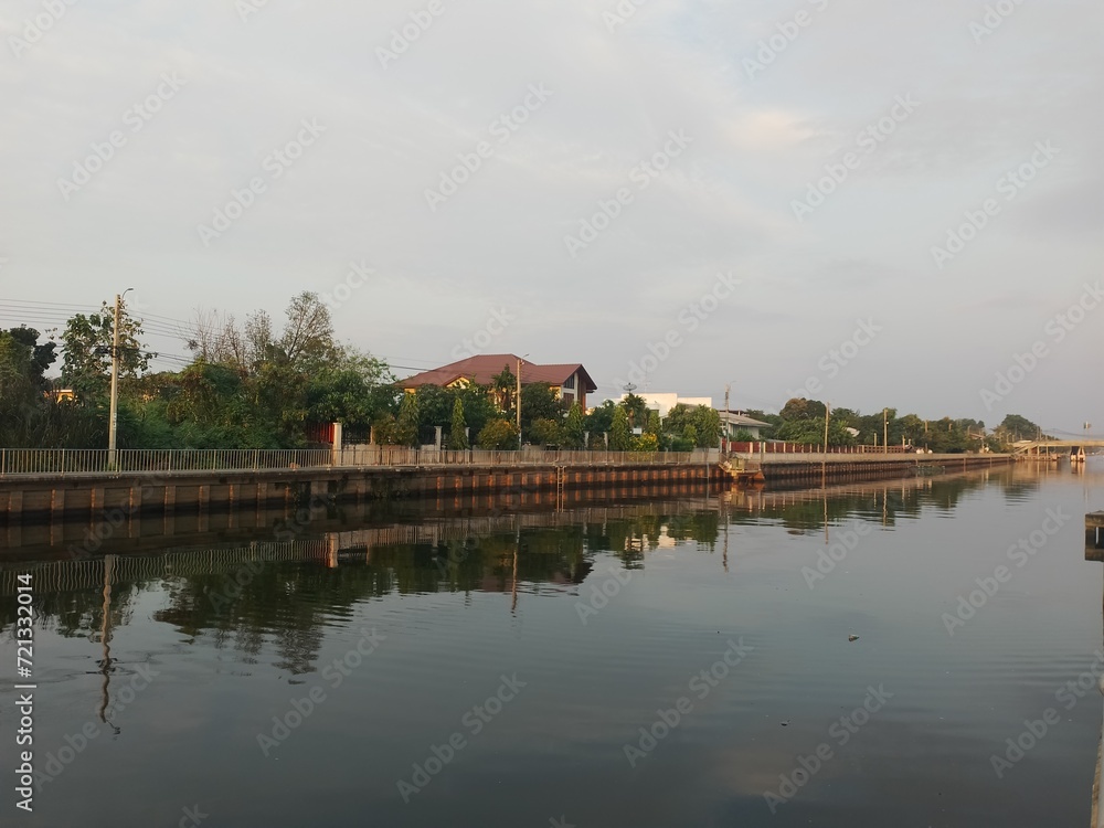 Obraz premium House by Water in Scenic Landscape with Trees and Sky Reflection
