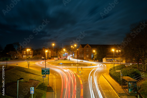 Car and lorry light trails on a roundabout in a small town