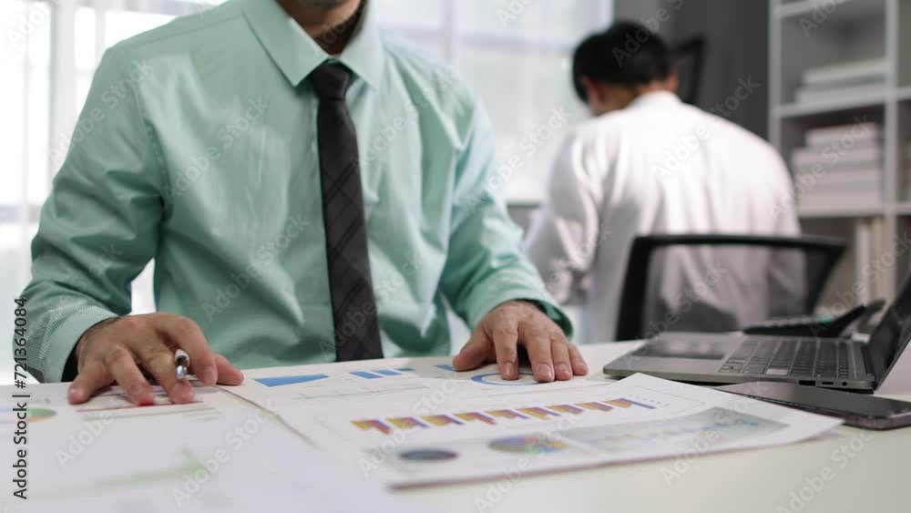 Businessman working with business documents is analyzing and auditing financial reports on the desk in the office. Businessman working with business documents is analyzing and auditing financial reports on the desk in the office.