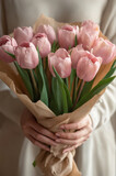Woman hands holding a bouquet of tulips in kraft paper.
