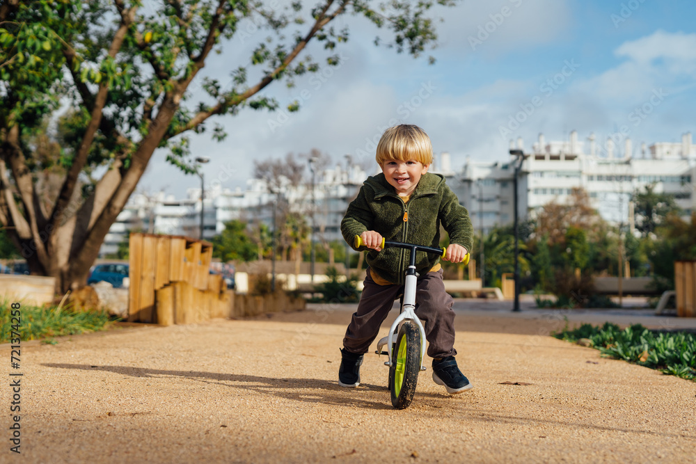 Obraz premium A little boy is on a bike ride.3 year old blond boy plays and enjoys a sunny day in the park on a bicycle