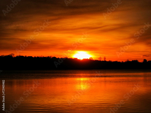 As the sun rose over the lake  the clouds in the sky turned orange and beautiful