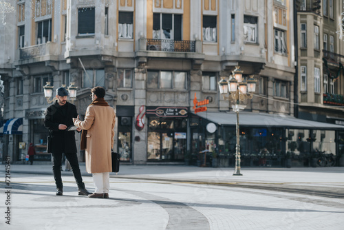 Dressed in stylish winter wear, two friends or colleagues are having a conversation on a well-lit, urban street, exuding a vibe of casual urban life and connection.