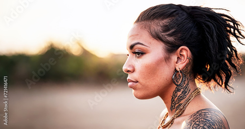 primo piano testa di giovane donna latino americana, vista di profilo, tatuaggi e capelli corvini photo