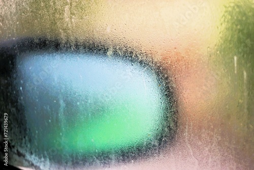 Abstraktes Motiv mit beschlagener Eisbedeckter Glasscheibe vor Autospiegel bei Frost, Sonne und Kälte am Morgen im Winter