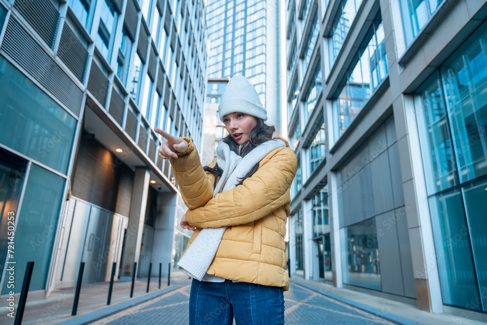 smiling young woman having fun time, using mobile phones outdoor in an urban winter city. people, communication, shopping and lifestyle concept