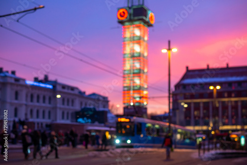 Blured picture of Oslo city centre. Urban Elegance: Glass Clock Tower and public transportation in Oslo.