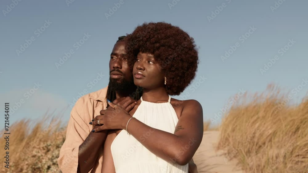 Elegant African man and woman with afro hairstyles embrace in a desert