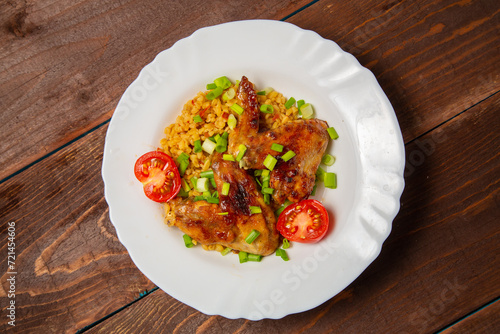 Chicken wings baked with bulgur, topped with green onions and garnished with cherry tomatoes