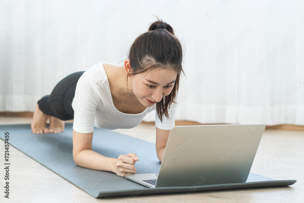 Fit, sporty asian young beautiful woman, girl doing yoga pose planking, watching trainer online on laptop computer, training in living room. Workout fitness exercise people in sportswear at home. Fit, sporty asian young beautiful woman, girl doing yoga pose planking, watching trainer online on laptop computer, training in living room. Workout fitness exercise people in sportswear at home.