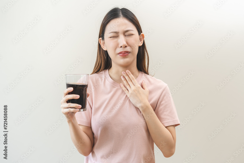 Acid reflux disease, suffer asian young woman, girl hand holding a glass of cola, have symptom gastroesophageal, heartburn pain on chest when drinking sparkling, soft water. Healthcare medical concept Acid reflux disease, suffer asian young woman, girl hand holding a glass of cola, have symptom gastroesophageal, heartburn pain on chest when drinking sparkling, soft water. Healthcare medical concept