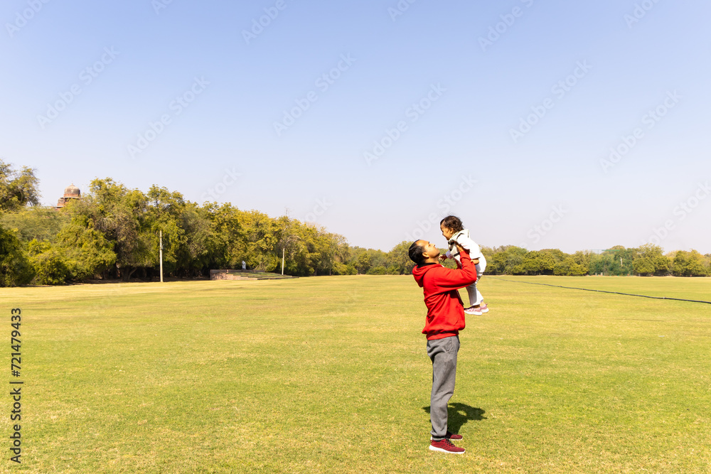 father holding son in hand at outdoor with bright blue sky at morning