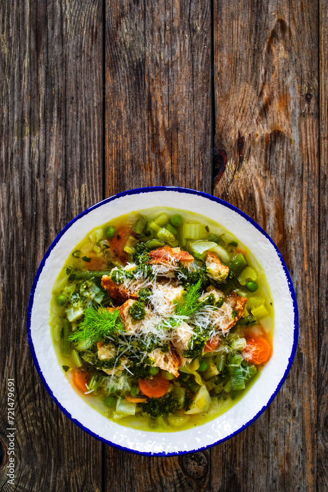 Pistou soup Nice - broth with basil pesto, bread, cheese and vegetables on wooden background in white bowl
Pistou soup Nice - broth with basil pesto, bread, cheese and vegetables on wooden background in white bowl