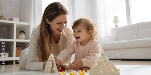 Happy mother and daughter are building in a tower, playing with a wooden construction set. Concept of leisure, development, education, happy pastime