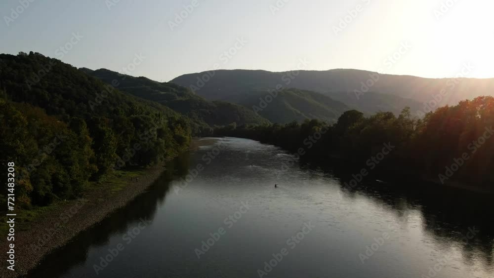 Sunset behind green wooded mountains and river in a valley Sunset behind green wooded mountains and river in a valley