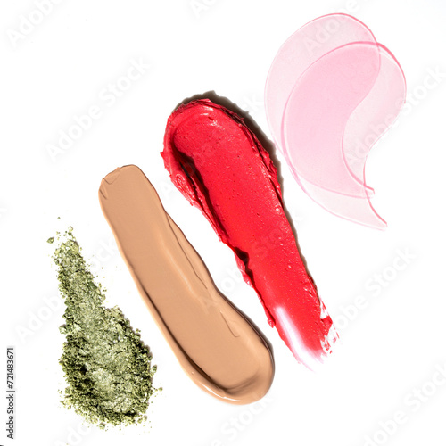 Textures of lipstick, foundation, eye shadow and eye patches on a white background.
