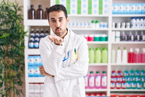 Handsome hispanic man working at pharmacy drugstore looking at the camera blowing a kiss with hand on air being lovely and sexy. love expression. © Krakenimages.com