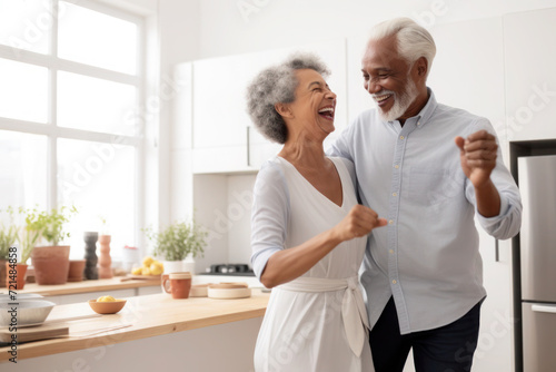 African multiracial married senior mature couple dancing in the kitchen