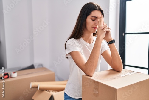 Young beautiful hispanic woman leaning on package with worried expression at new home