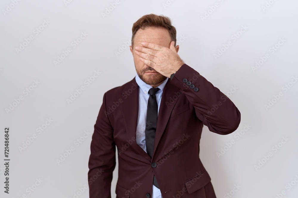 Middle age business man with beard wearing suit and tie covering eyes with hand, looking serious and sad. sightless, hiding and rejection concept Middle age business man with beard wearing suit and tie covering eyes with hand, looking serious and sad. sightless, hiding and rejection concept