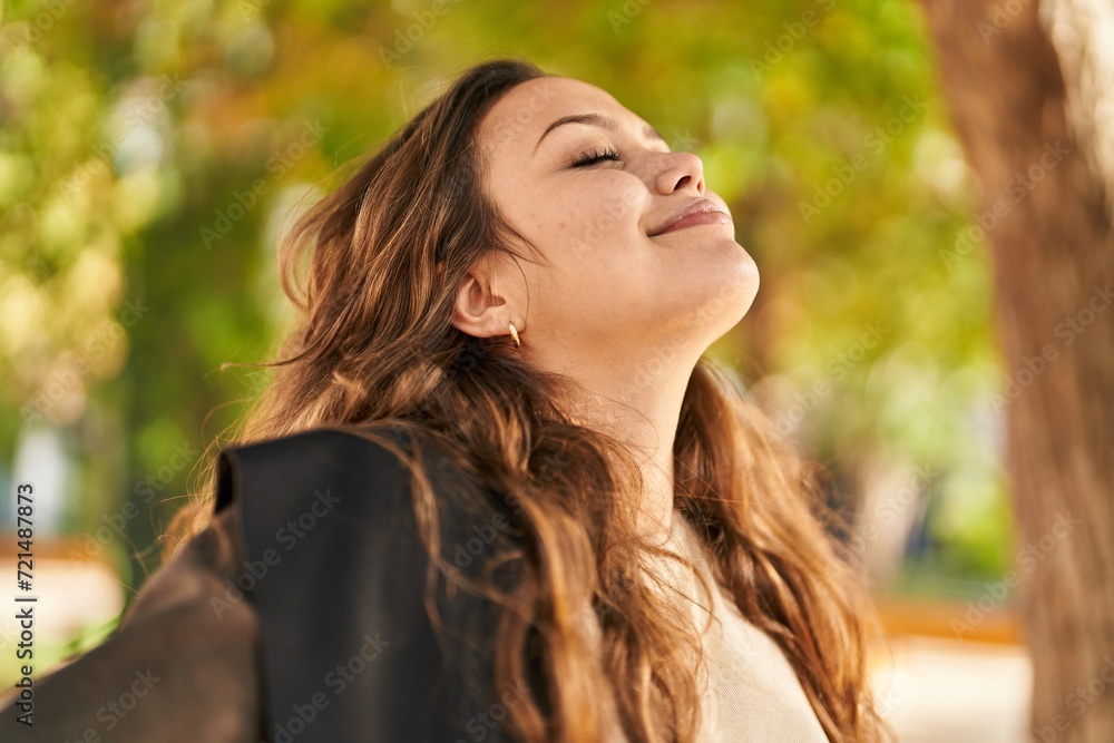 Fototapeta premium Young beautiful hispanic woman breathing with closed eyes at park