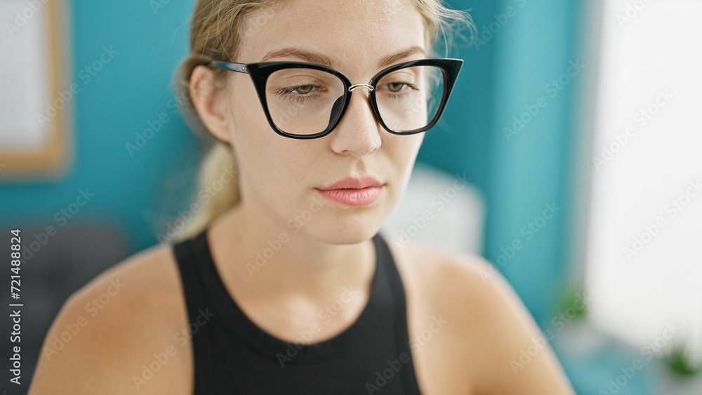 Young blonde woman business worker sitting on table with serious face at the office Young blonde woman business worker sitting on table with serious face at the office
