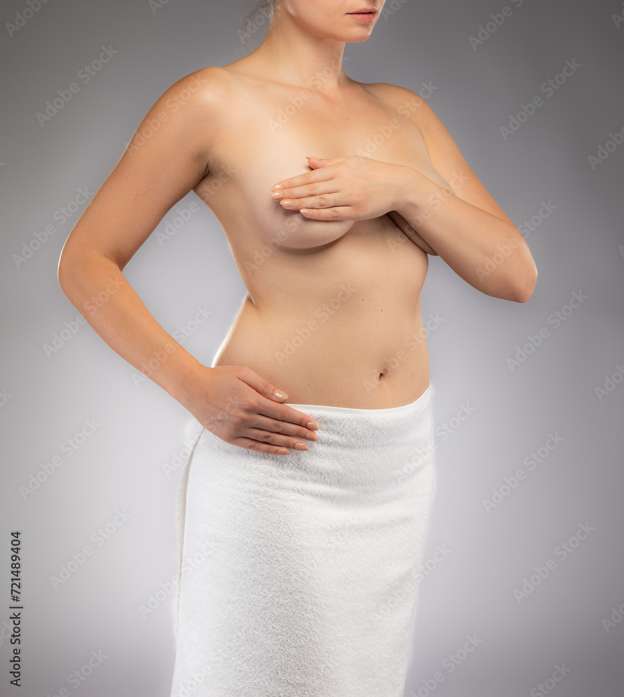 Woman examining her breast on gray background
