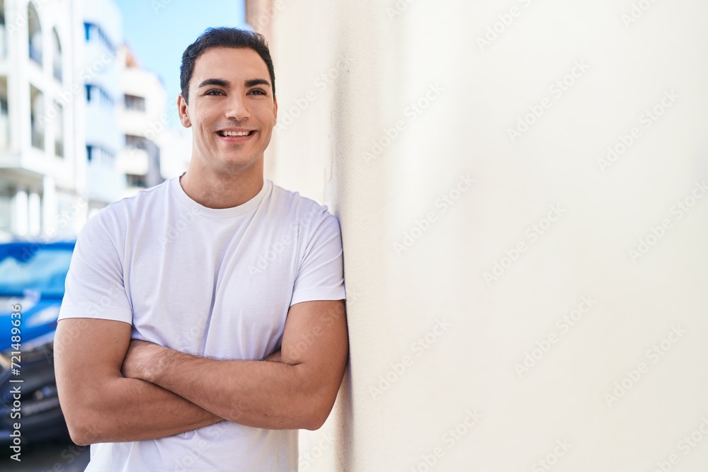 Young hispanic man standing with arms crossed gesture at street Young hispanic man standing with arms crossed gesture at street