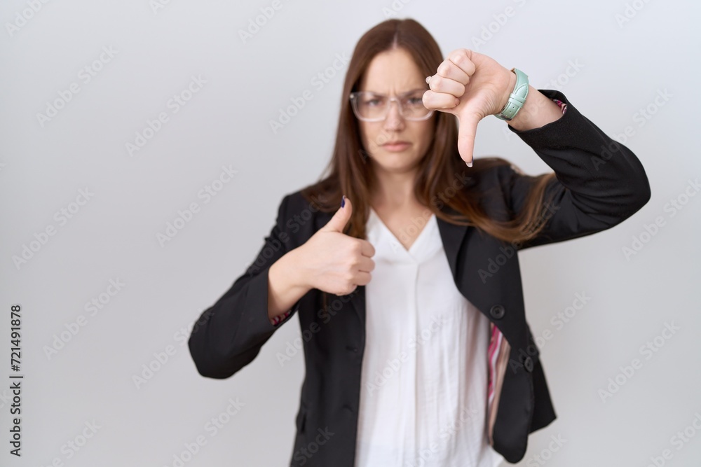 Beautiful brunette woman wearing business jacket and glasses doing thumbs up and down, disagreement and agreement expression. crazy conflict Beautiful brunette woman wearing business jacket and glasses doing thumbs up and down, disagreement and agreement expression. crazy conflict