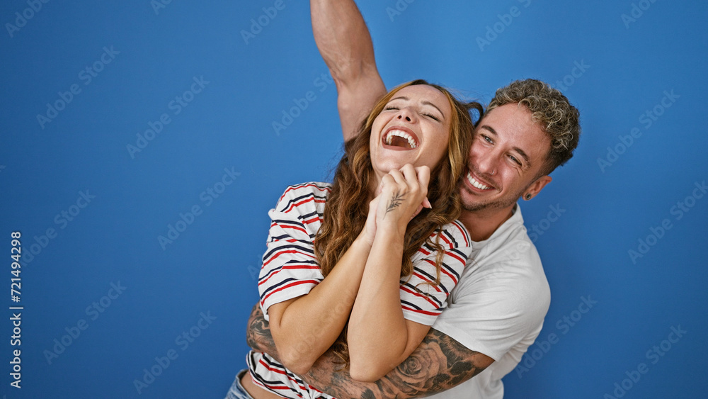 Naklejka premium Happy couple embracing and laughing together against a blue background, depicting love and joy in a relationship