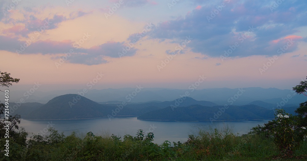 serene twilight sunset sky with hues of pink purple overlooks a tranquil lake nestled among layers of mountain silhouettes