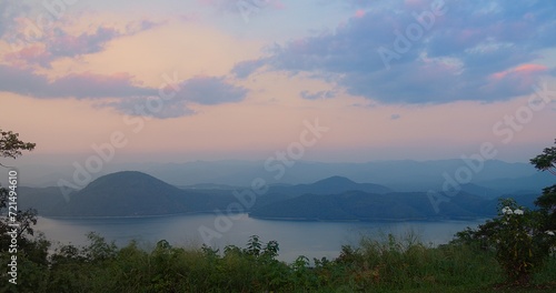 serene twilight sunset sky with hues of pink purple overlooks a tranquil lake nestled among layers of mountain silhouettes