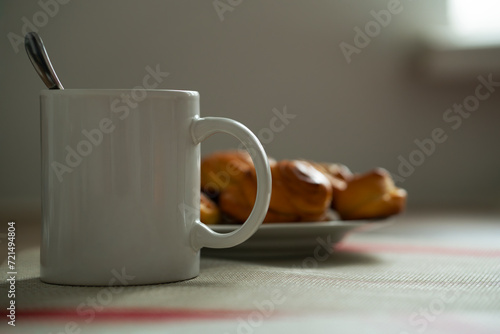 a cup of coffee and homemade buns on a plate.