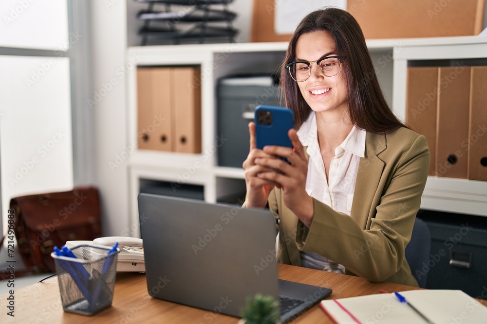 Young beautiful hispanic woman business worker using smartphone working at office