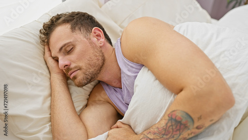 Handsome young man with a beard sleeping peacefully in a comfortable white bed indoors