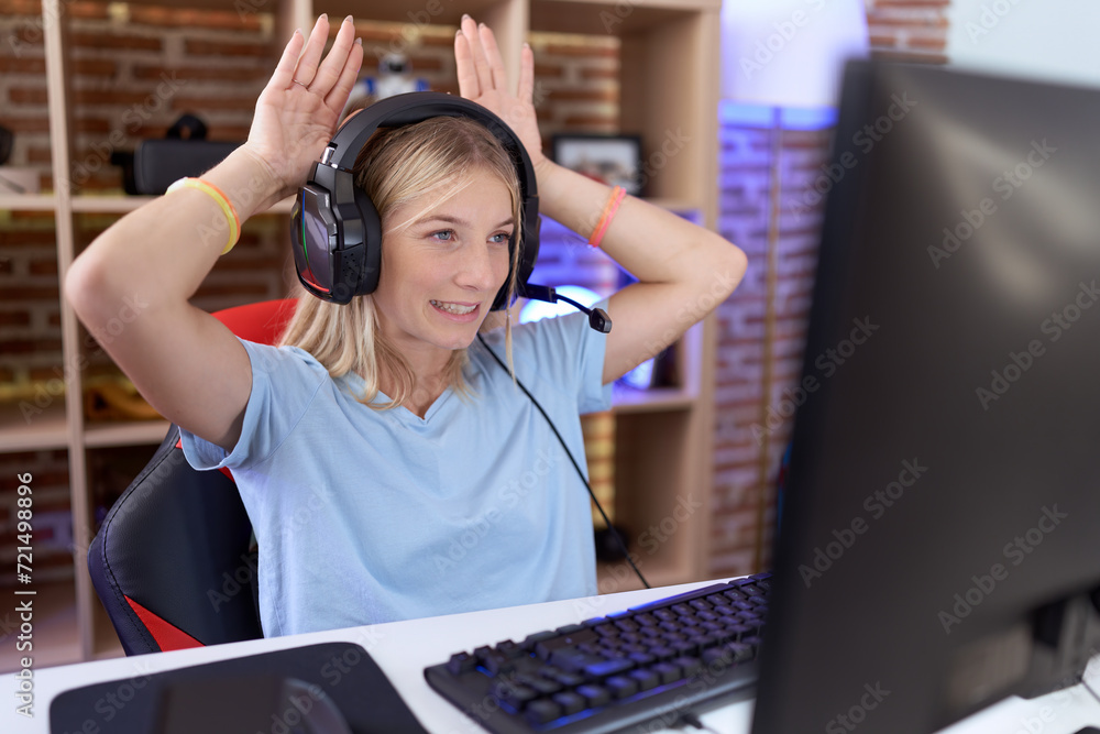 Young caucasian woman playing video games wearing headphones doing bunny ears gesture with hands palms looking cynical and skeptical. easter rabbit concept. Young caucasian woman playing video games wearing headphones doing bunny ears gesture with hands palms looking cynical and skeptical. easter rabbit concept.