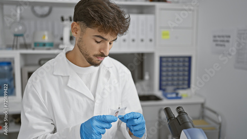 Arabian young man scientist, deeply concentrated in his analysis, looking at a sample in lab with focus, balancing research and safety with professionalism in science photo
