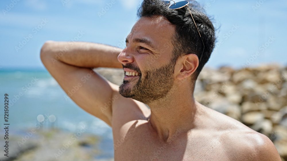 Young hispanic man tourist combing hair with hands shirtless at the beach Young hispanic man tourist combing hair with hands shirtless at the beach