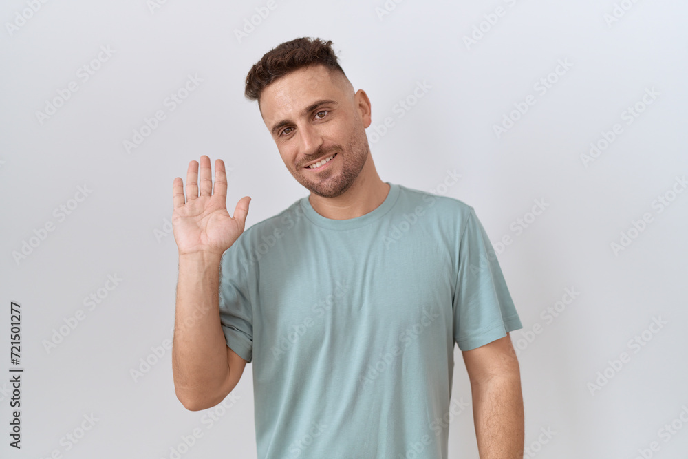 Hispanic man with beard standing over white background waiving saying hello happy and smiling, friendly welcome gesture Hispanic man with beard standing over white background waiving saying hello happy and smiling, friendly welcome gesture