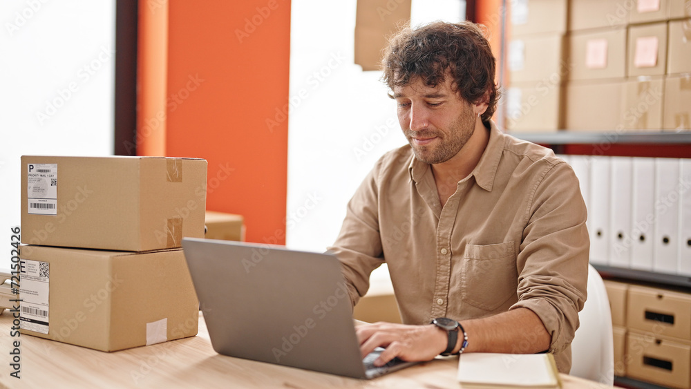 Young hispanic man ecommerce business worker typing on computer smiling at office Young hispanic man ecommerce business worker typing on computer smiling at office