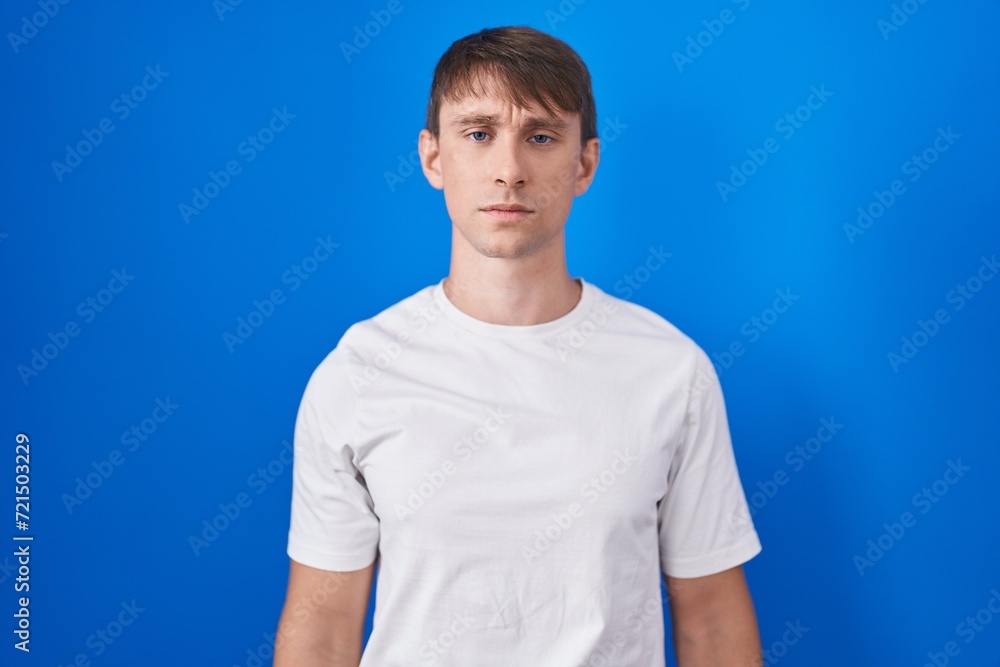 Caucasian blond man standing over blue background skeptic and nervous, frowning upset because of problem. negative person. Caucasian blond man standing over blue background skeptic and nervous, frowning upset because of problem. negative person.