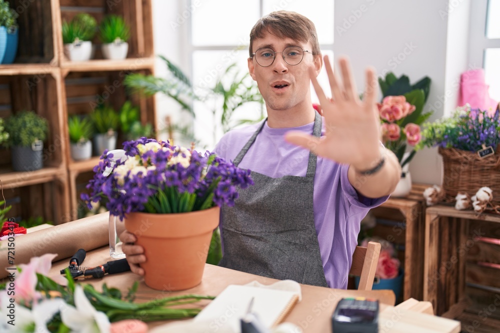 Caucasian blond man working at florist shop doing stop gesture with hands palms, angry and frustration expression