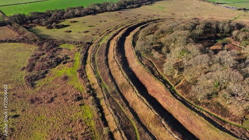 Aerial shot flying down towards a series of concentric ditches and ramparts surrounding an ancient iron age hill fort at Badbury Rings photo