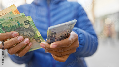 A woman holds south african rand on a city street, exemplifying finance, economy, shopping, or travel in an urban setting. photo