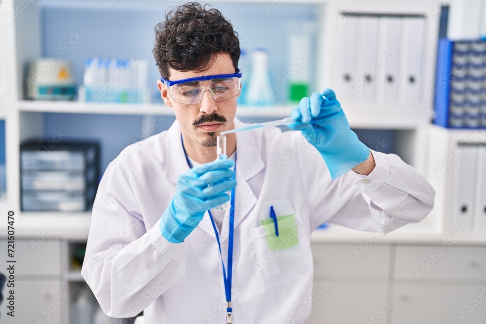 Young caucasian man scientist pouring liquid on test tube at laboratory Young caucasian man scientist pouring liquid on test tube at laboratory